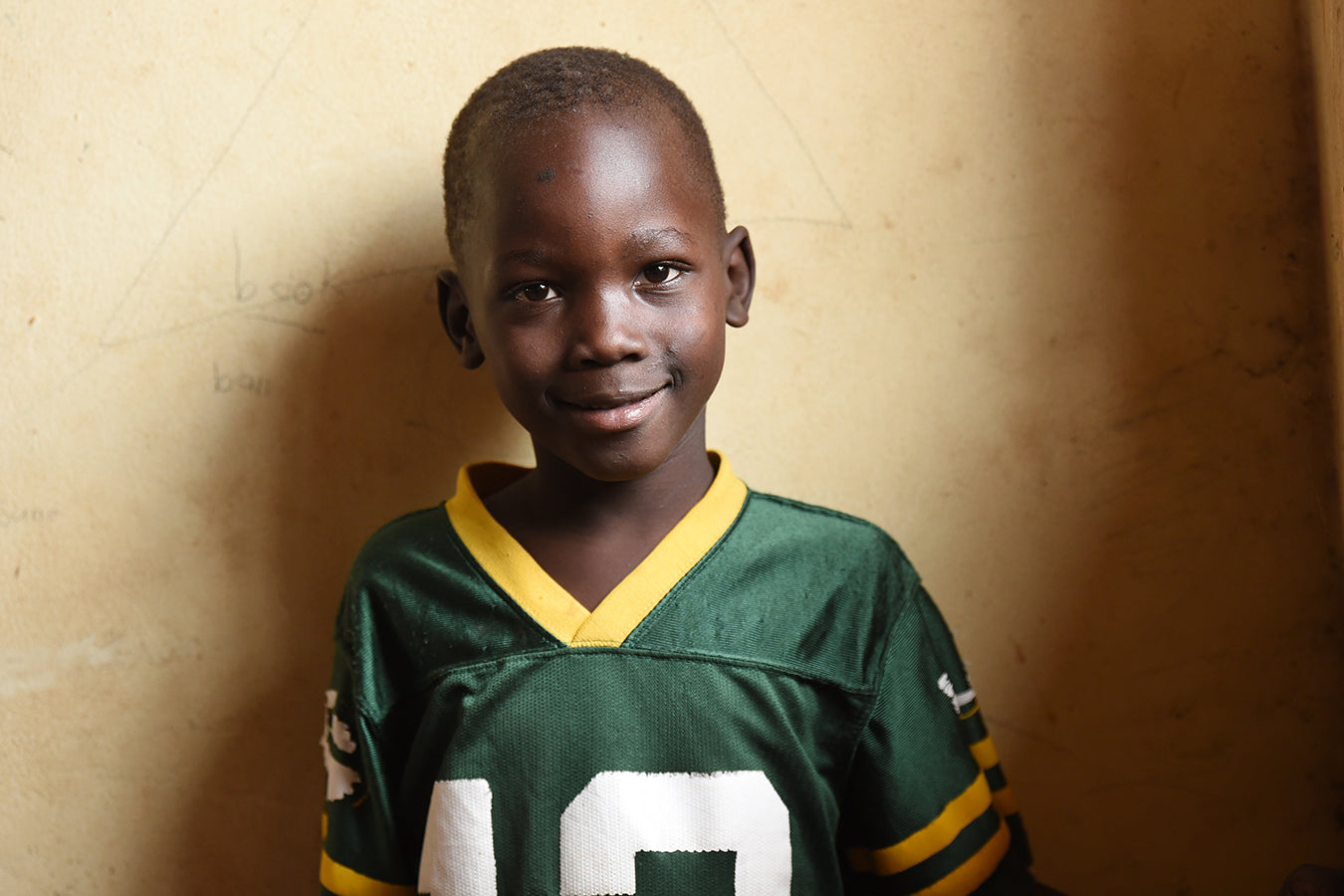 Smiling Ugandan boy wearing a green football jersey