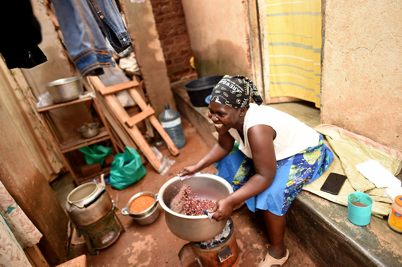African woman roasting peanuts in front of her home
